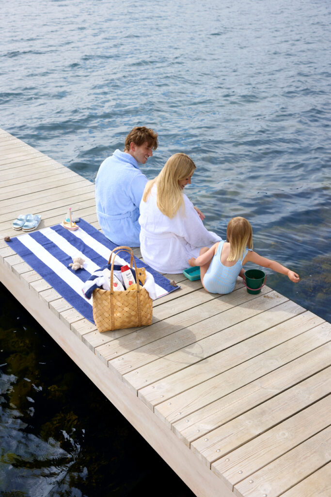 En barnfamilj sitter på en brygga i Sverige under sommaren