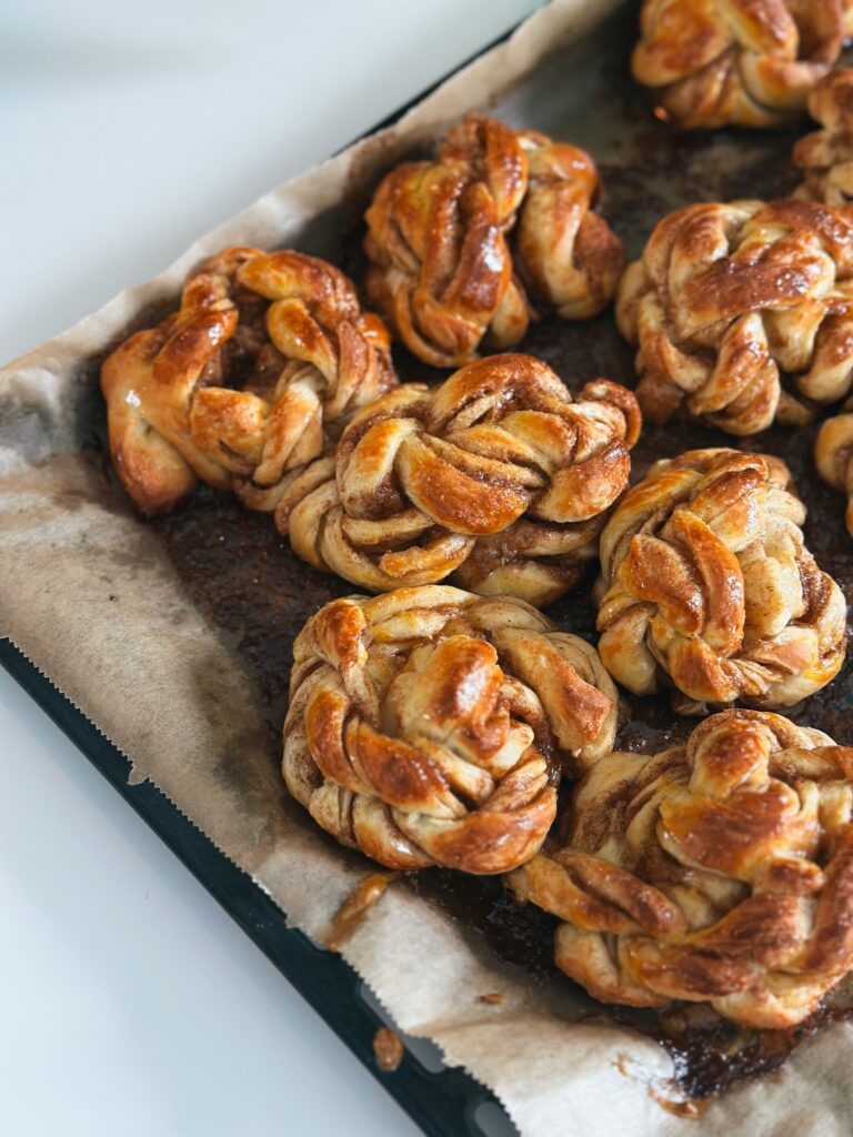 9 flätade bullar som ligger i en hög på en ugnsplåt